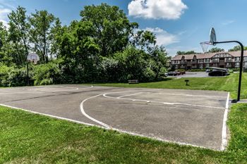 A basketball court surrounded by trees and a building in the background